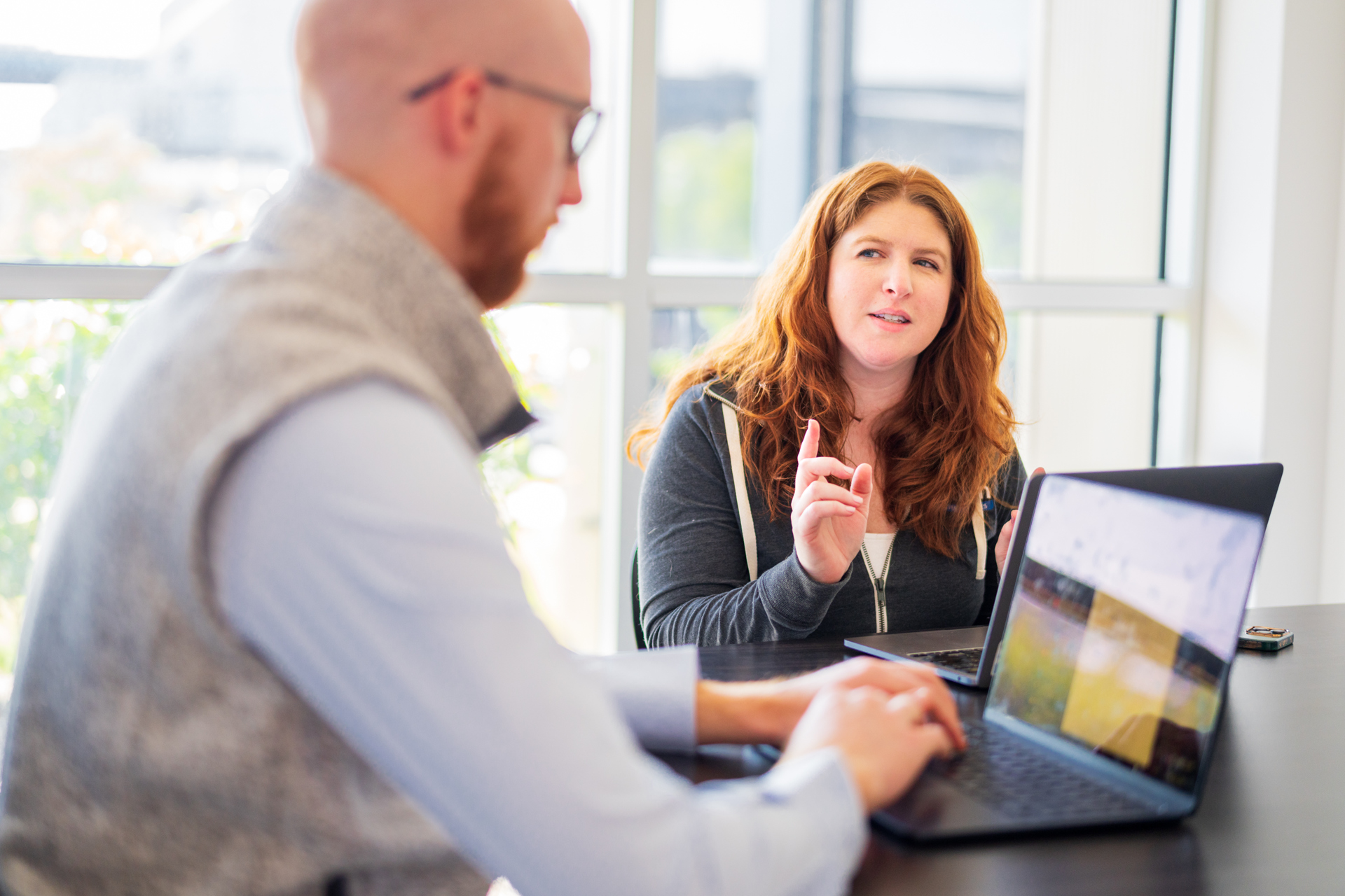 Two Stamm employees sitting at a conference table with their laptops